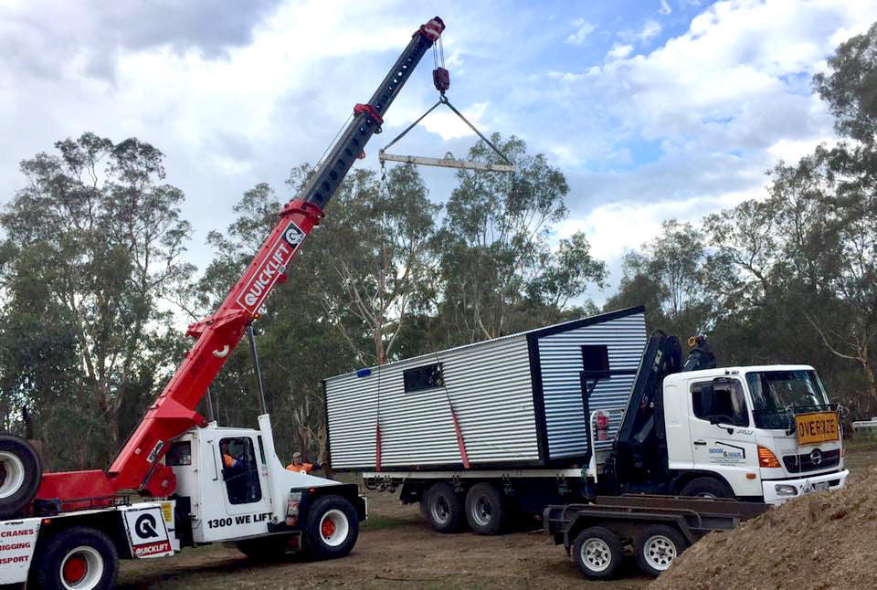 House on truck bed being lifted by crane